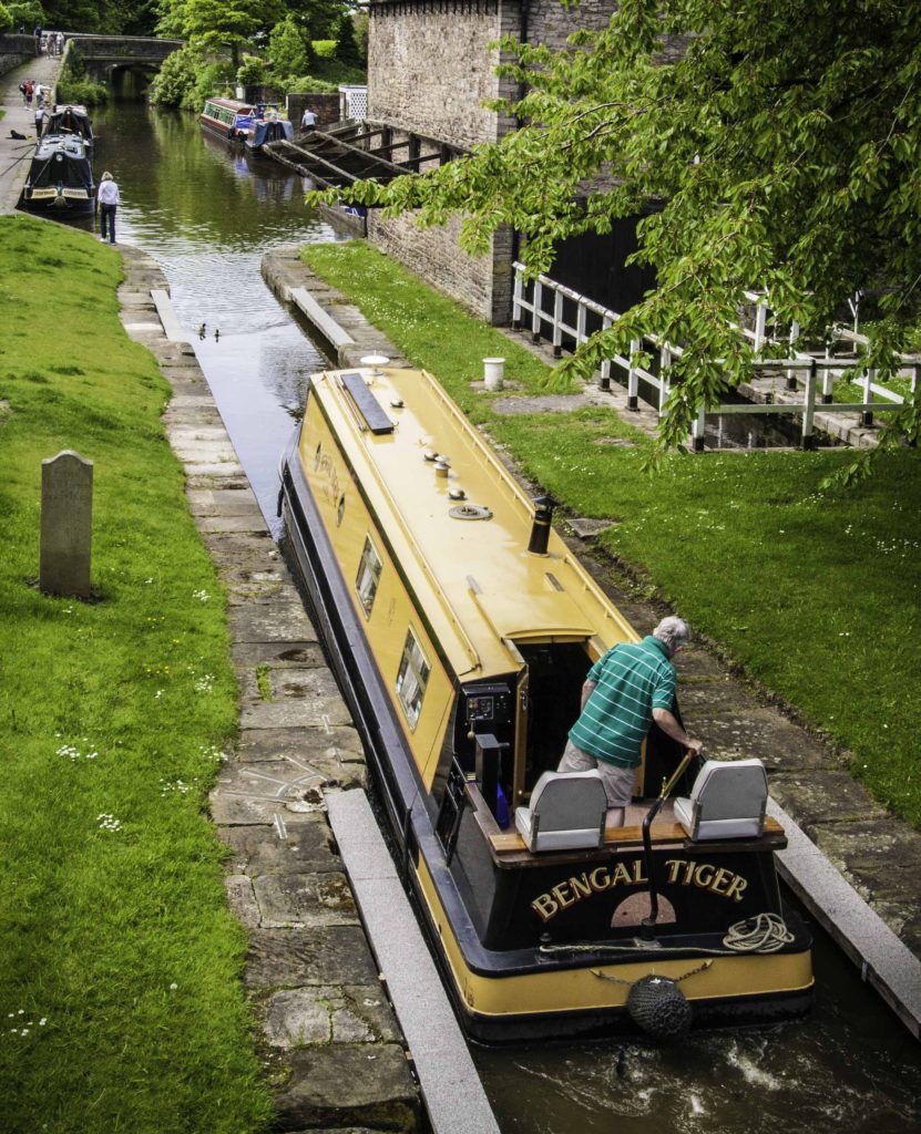 A brightly colored "Bengal Tiger" emerges from the locks at Marple onto the Macclesfield Canal, Cheshire Ring Canals, Cheshire, UK