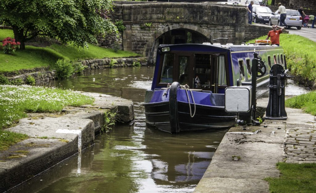 A bit of thoughtful head scratching helps getting a narrow long canal boat into a lock at Marple Junction, Cheshire Ring Canals, Cheshire, UK