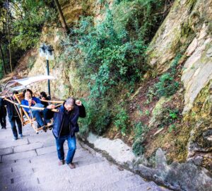 Porters carrying paying passengers to the top of BaidiCheng stairs, White Emperor City, Yangtze River Three Gorges Cruise, Chongqing, China 